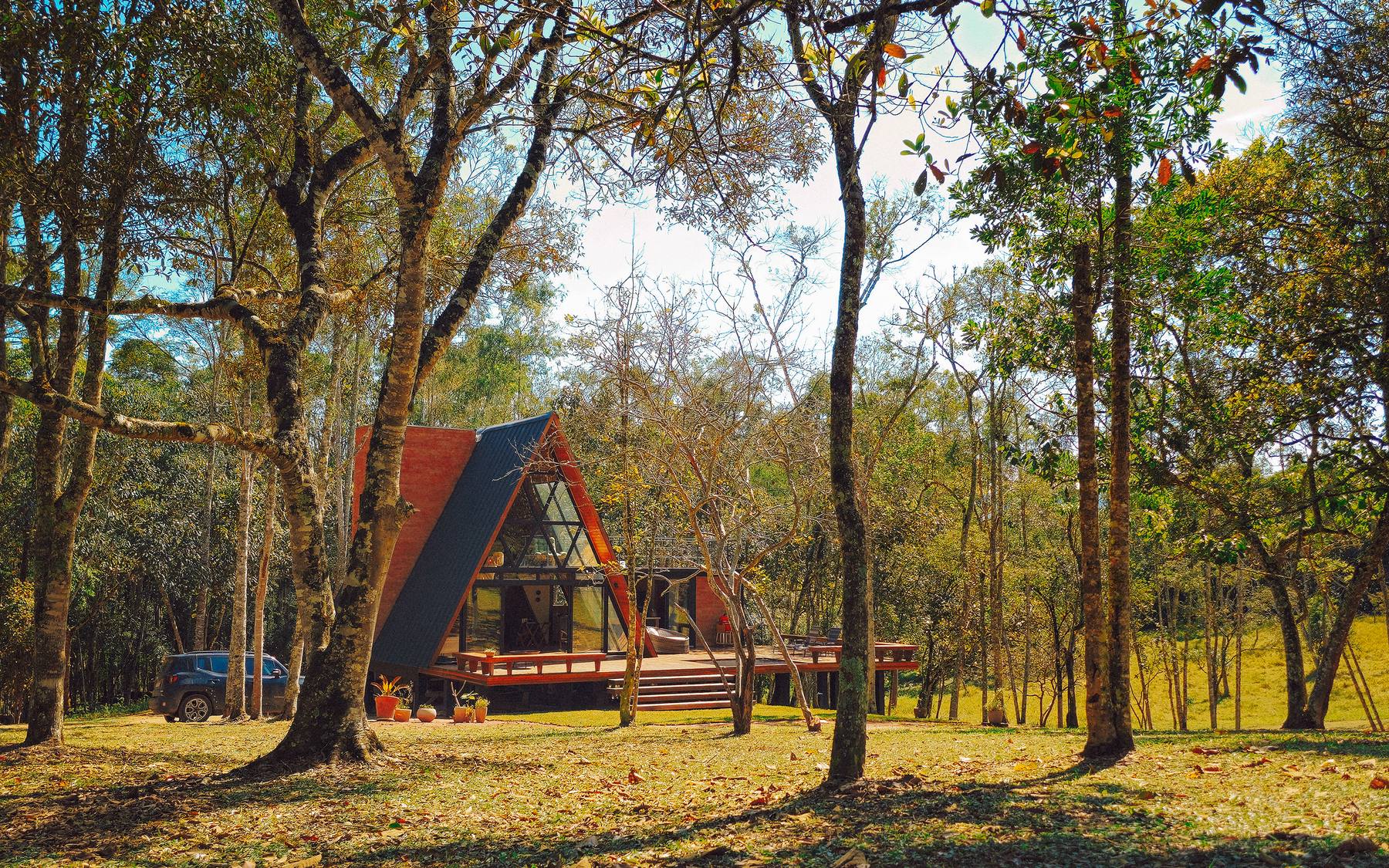 O chalé A-frame visto de longe, entre as árvores da Serra da Mantiqueira